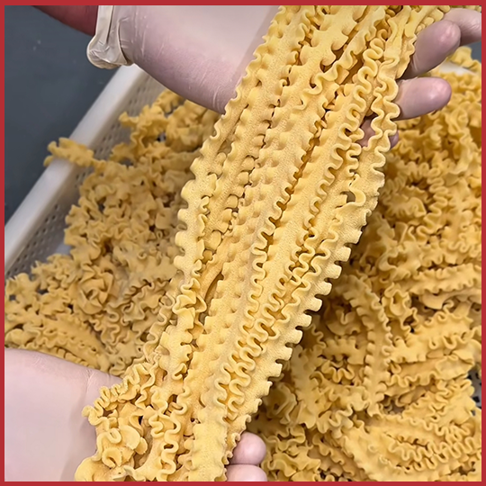 Fresh Mafalda pasta in workers gloved hands