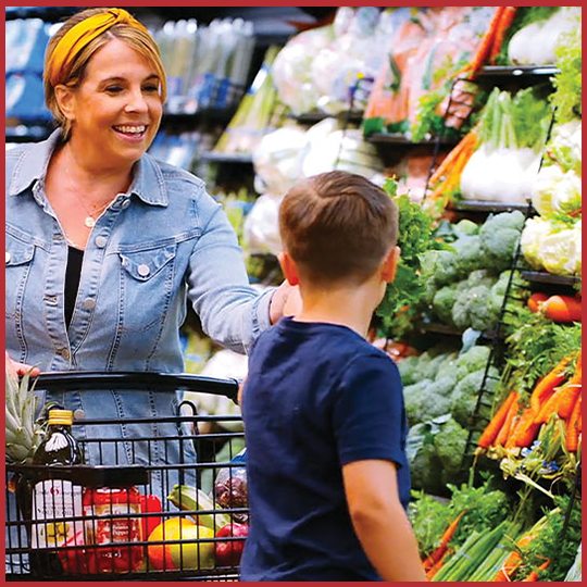 A woman handing her son something in the Uncle Giuseppe's produce section